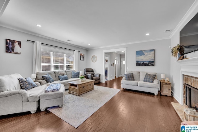 living room with a brick fireplace, crown molding, visible vents, and dark wood-type flooring