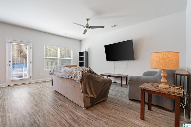 living room with visible vents, baseboards, a ceiling fan, and wood finished floors