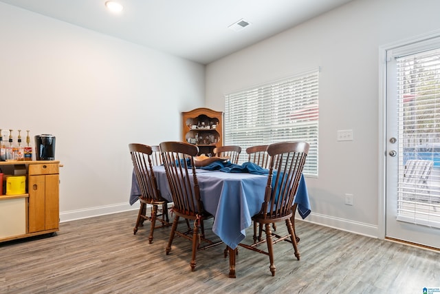 dining space featuring wood finished floors, visible vents, and baseboards