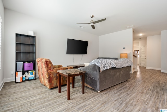 living room featuring visible vents, a ceiling fan, baseboards, and wood finished floors