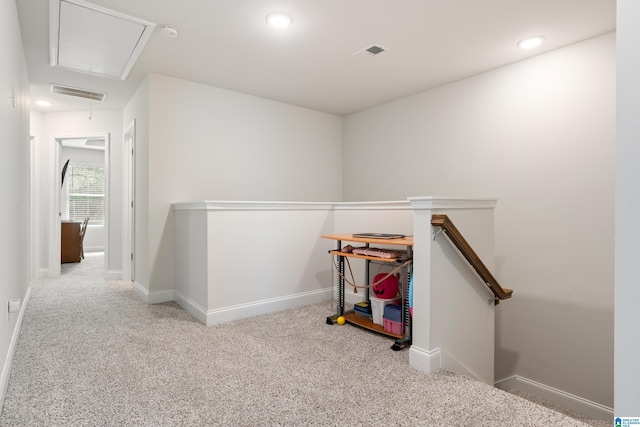 hall with an upstairs landing, visible vents, attic access, and carpet floors