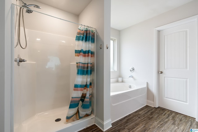 full bathroom featuring wood finished floors, a stall shower, and a bath