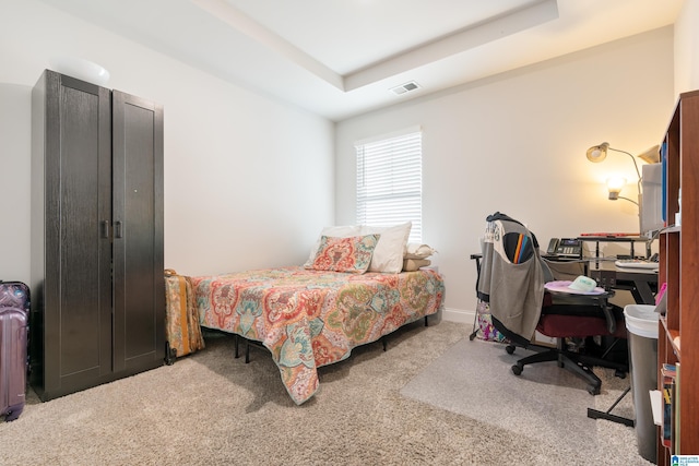 bedroom with a raised ceiling, visible vents, and carpet floors