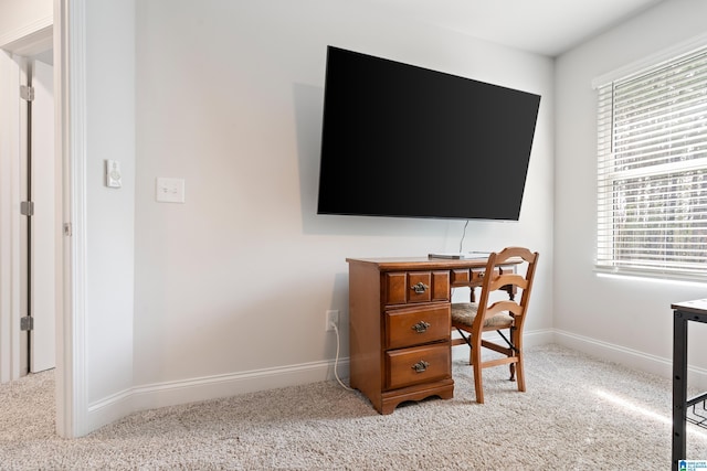 office area featuring baseboards and light carpet