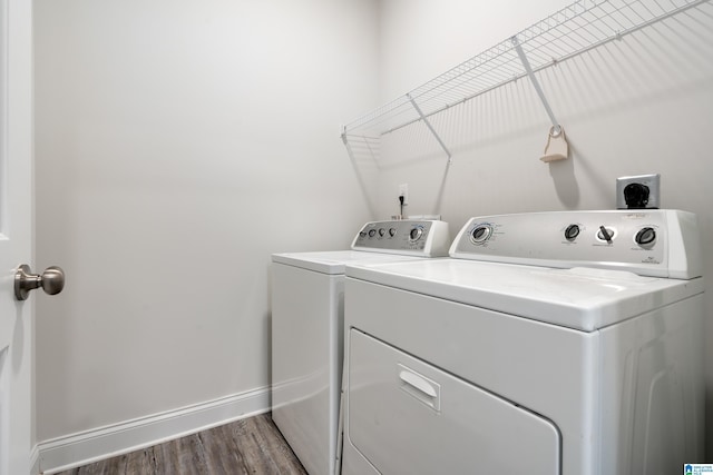 laundry area featuring laundry area, washing machine and dryer, baseboards, and wood finished floors