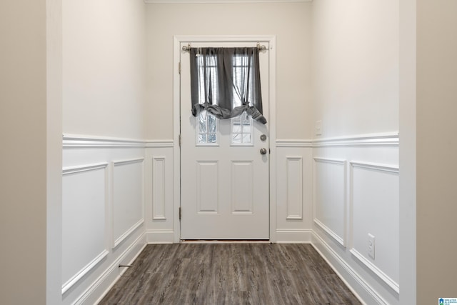 doorway with dark wood finished floors, wainscoting, and a decorative wall