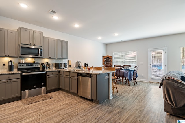 kitchen with visible vents, a peninsula, gray cabinets, appliances with stainless steel finishes, and tasteful backsplash