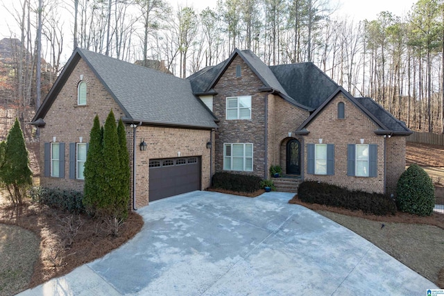 view of front of house with concrete driveway, brick siding, an attached garage, and roof with shingles