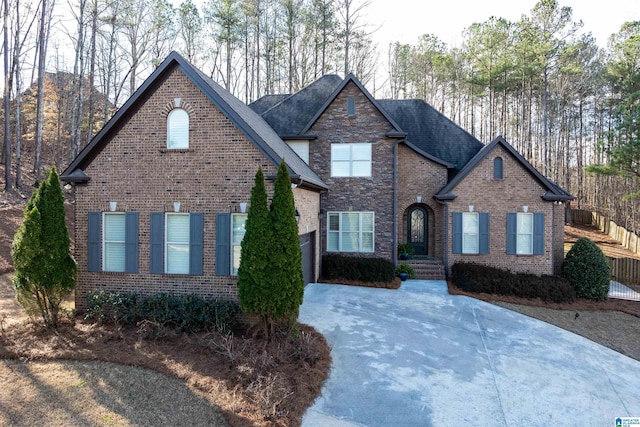 view of front of home with a shingled roof, stone siding, brick siding, and driveway