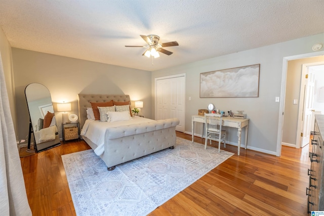 bedroom featuring a textured ceiling, a closet, baseboards, and wood finished floors