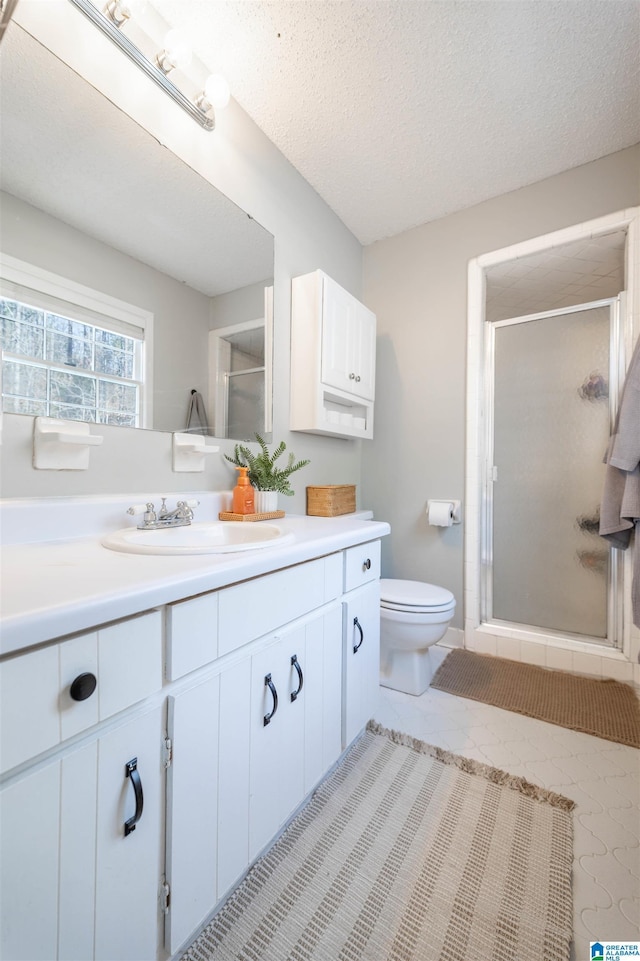 full bath with a textured ceiling, toilet, a shower stall, and vanity