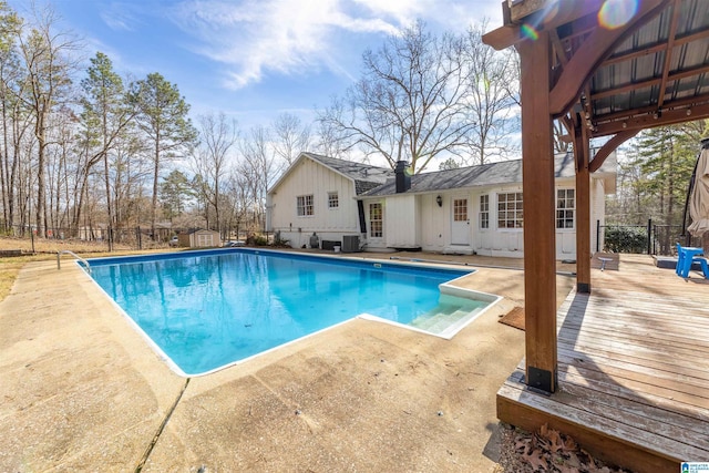 view of swimming pool with central AC unit, fence, a fenced in pool, and an outbuilding