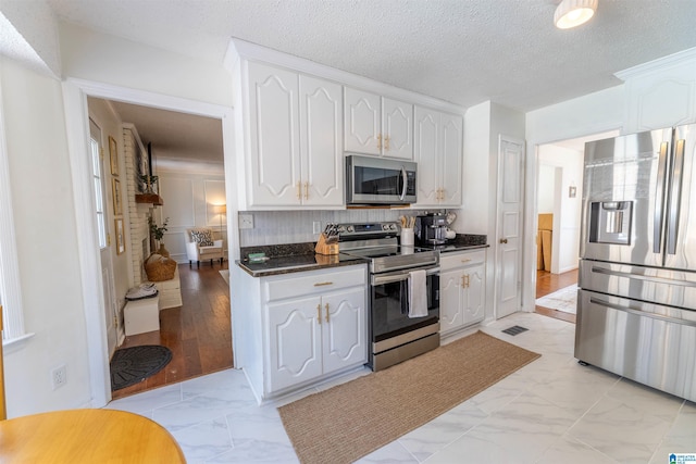 kitchen with appliances with stainless steel finishes, marble finish floor, and white cabinets