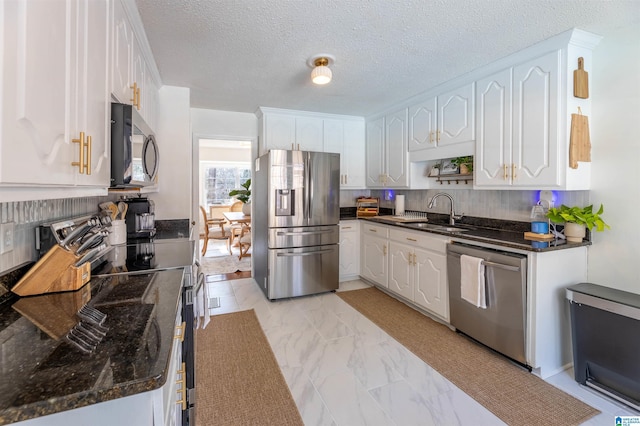 kitchen with marble finish floor, white cabinetry, appliances with stainless steel finishes, and a sink