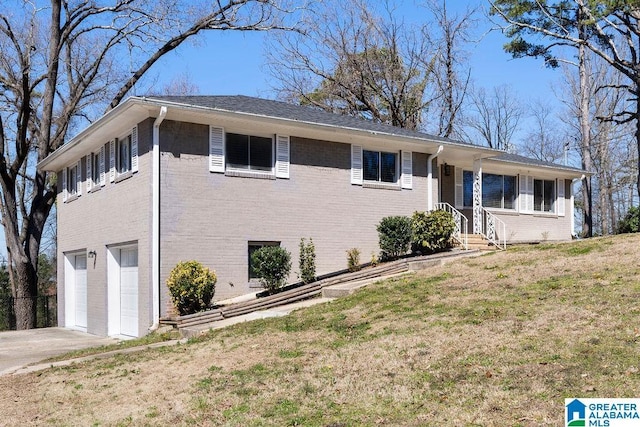 view of front of home featuring driveway, a garage, a front yard, and brick siding