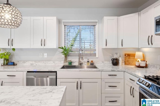 kitchen with pendant lighting, stainless steel appliances, white cabinetry, a sink, and light stone countertops