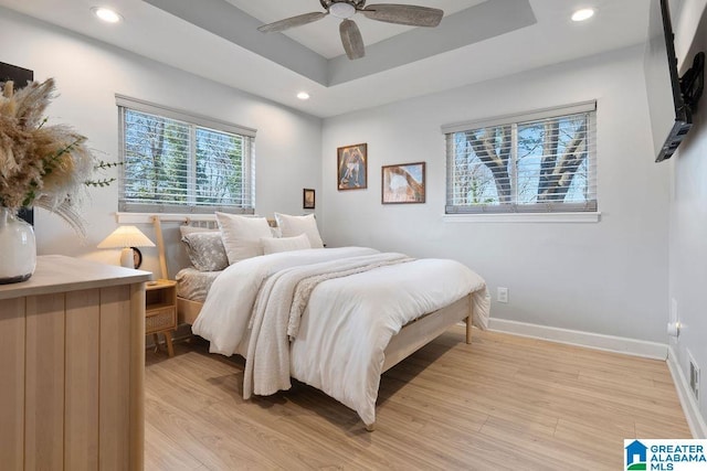 bedroom featuring recessed lighting, a raised ceiling, light wood-style floors, a ceiling fan, and baseboards