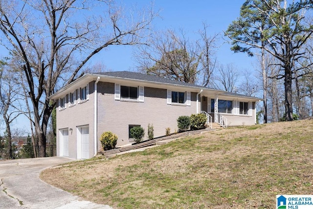 view of front of house with a garage, a front yard, brick siding, and driveway