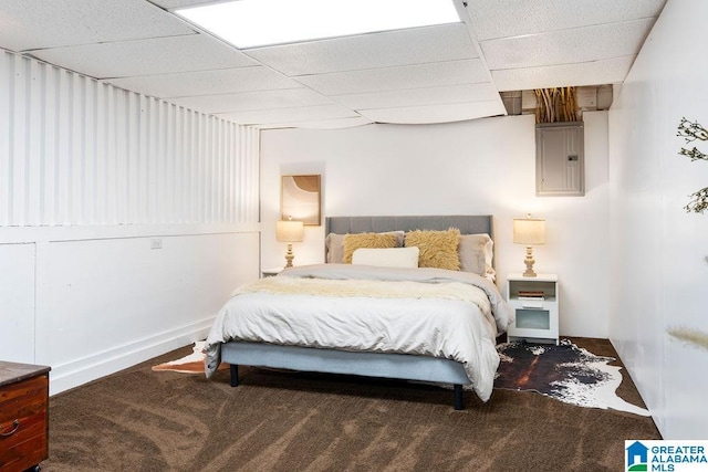 bedroom with carpet, electric panel, and a drop ceiling