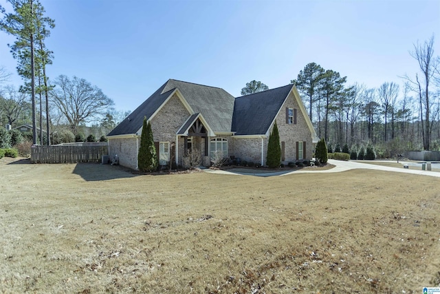 view of front facade with fence, a front lawn, and brick siding