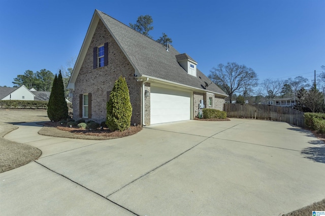 view of side of home with driveway, a garage, fence, and brick siding