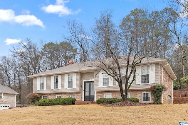 split foyer home featuring a front lawn, a chimney, and brick siding