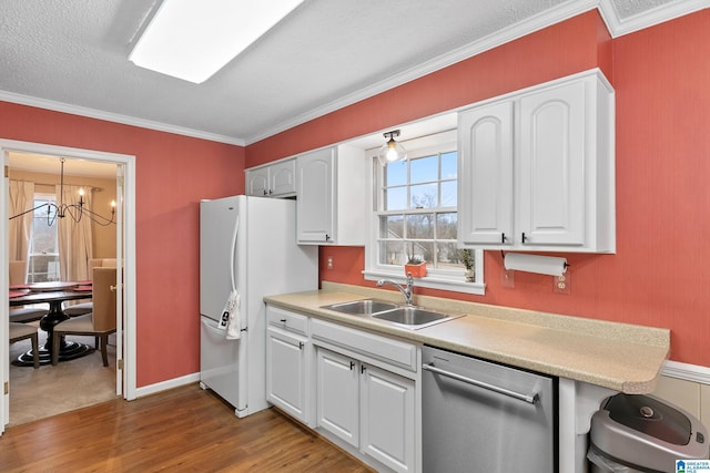 kitchen with dishwasher, wood finished floors, freestanding refrigerator, crown molding, and a sink