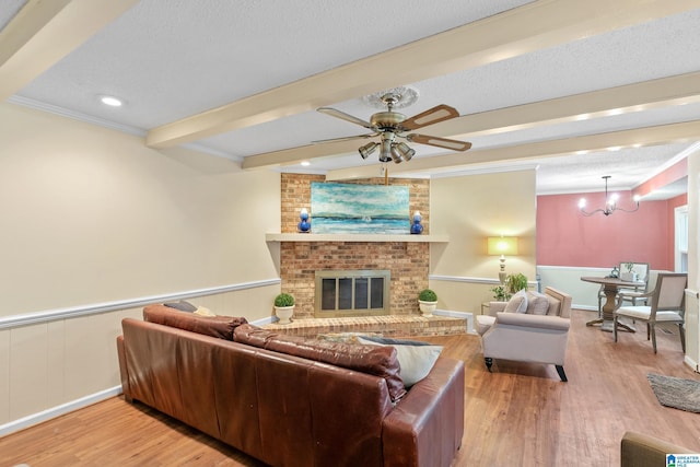 living area with a textured ceiling, beamed ceiling, a fireplace, and wood finished floors