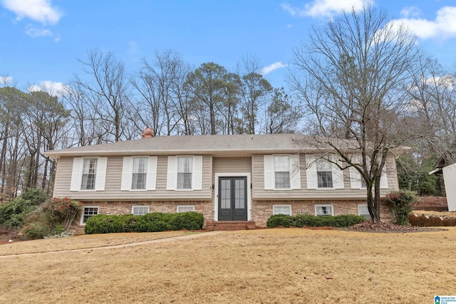 bi-level home with french doors, a chimney, and a front lawn