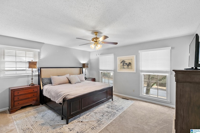 bedroom featuring light carpet, multiple windows, and a textured ceiling