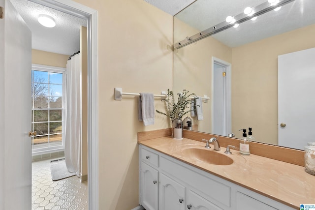 full bathroom with a textured ceiling and vanity