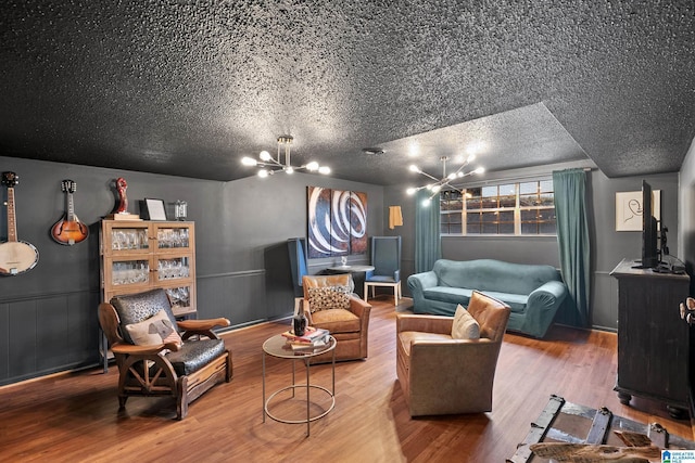 sitting room featuring a textured ceiling, a chandelier, wood finished floors, and wainscoting