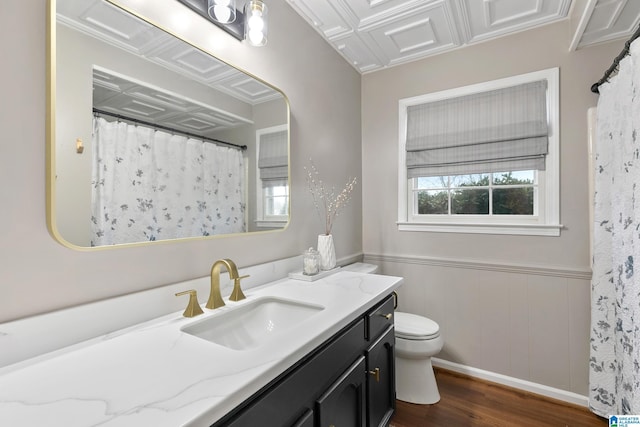 full bathroom with wainscoting, plenty of natural light, toilet, and wood finished floors