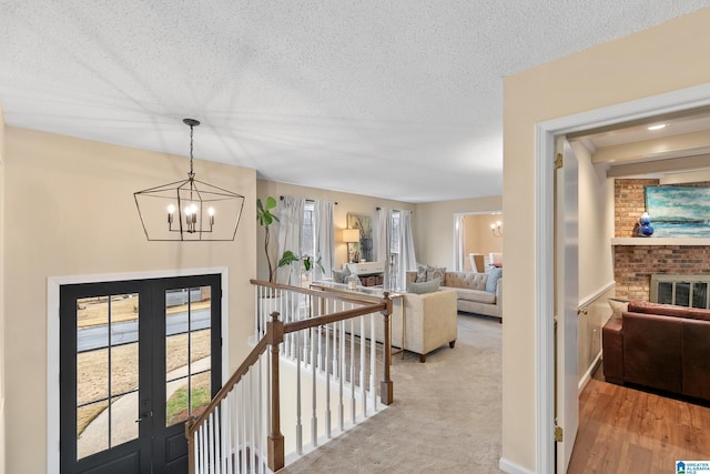 corridor featuring a chandelier, a textured ceiling, and an upstairs landing