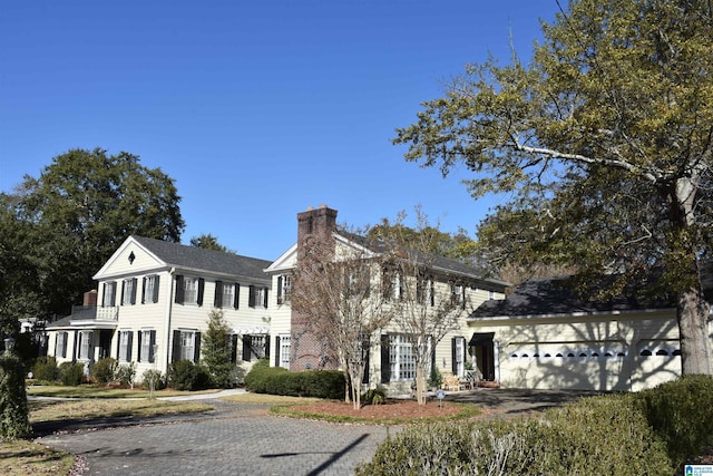 colonial house featuring a garage, driveway, and a chimney