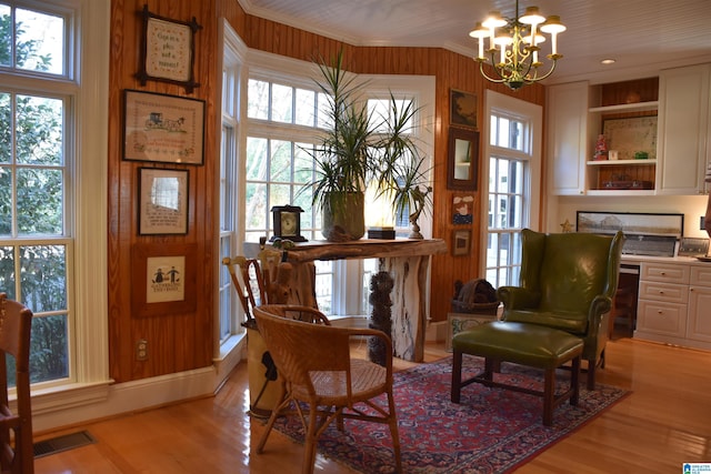 sitting room featuring light wood-style floors, crown molding, visible vents, and built in desk