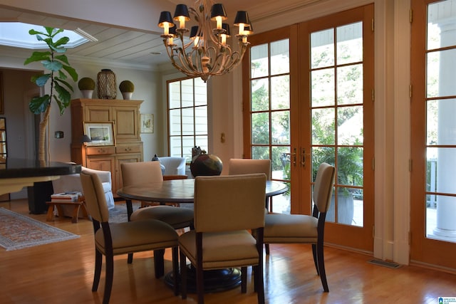 dining room with visible vents, ornamental molding, a chandelier, and light wood-style flooring