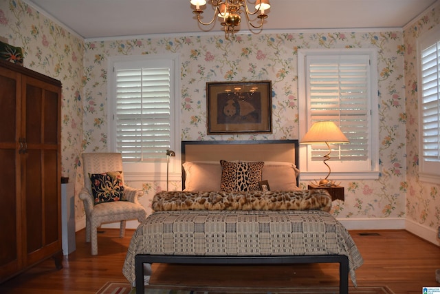 bedroom featuring wood finished floors, baseboards, an inviting chandelier, and wallpapered walls