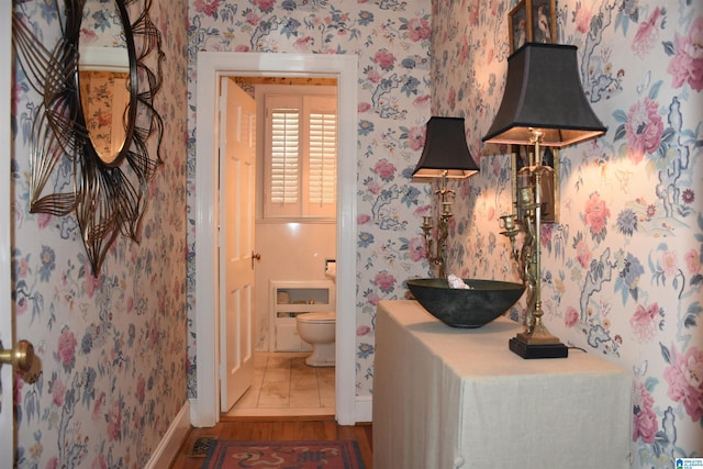 interior space featuring wood finished floors, baseboards, toilet, and wallpapered walls