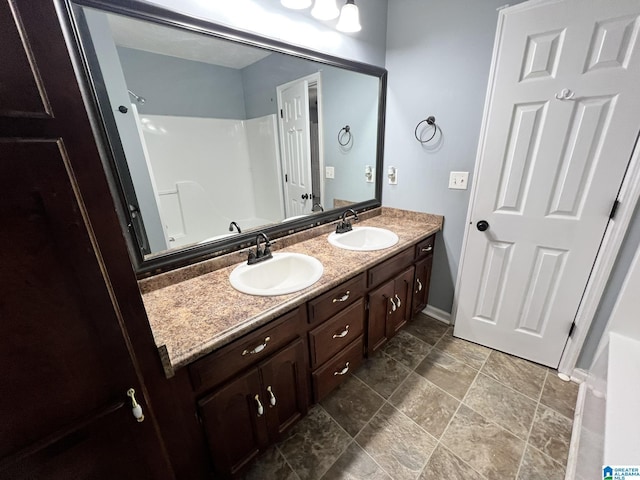 bathroom with double vanity, a sink, and baseboards