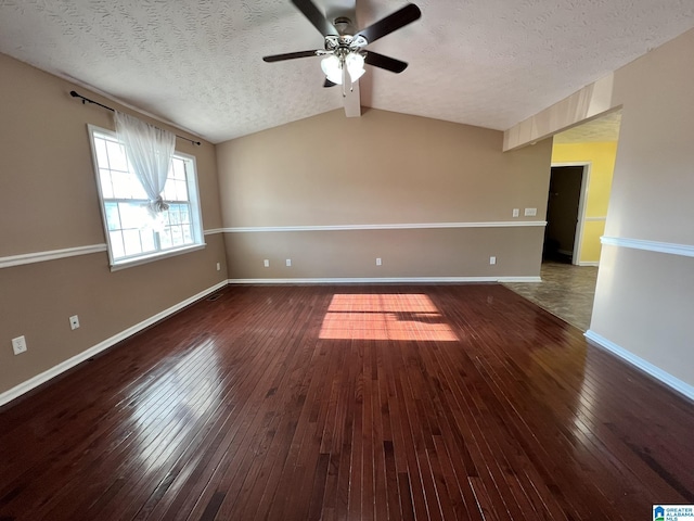 unfurnished room with vaulted ceiling with beams, wood-type flooring, a ceiling fan, a textured ceiling, and baseboards