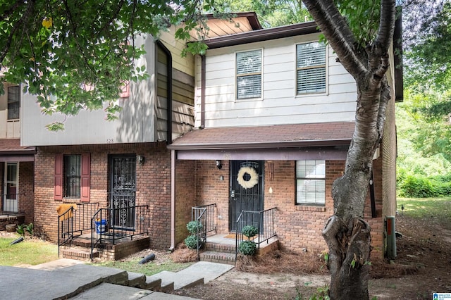 view of front of house with a shingled roof and brick siding