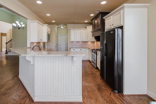 kitchen featuring light stone counters, ornamental molding, dark wood-style flooring, a peninsula, and stainless steel appliances