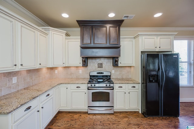 kitchen with wood finished floors, black fridge with ice dispenser, backsplash, wall chimney exhaust hood, and gas stove