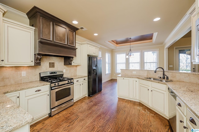 kitchen featuring stainless steel appliances, a raised ceiling, visible vents, light wood-style flooring, and a sink