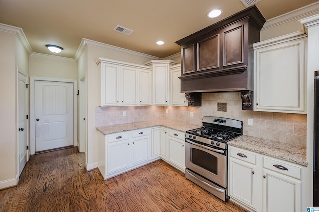 kitchen featuring tasteful backsplash, visible vents, ornamental molding, light wood-style floors, and stainless steel range with gas cooktop