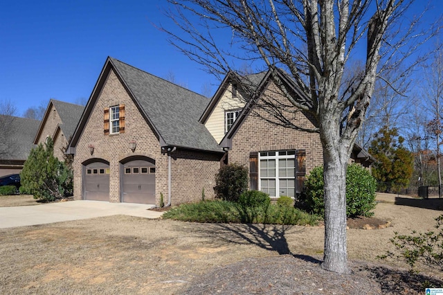 view of front of property featuring brick siding, driveway, and roof with shingles