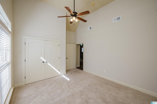 unfurnished bedroom with high vaulted ceiling, carpet, visible vents, and baseboards