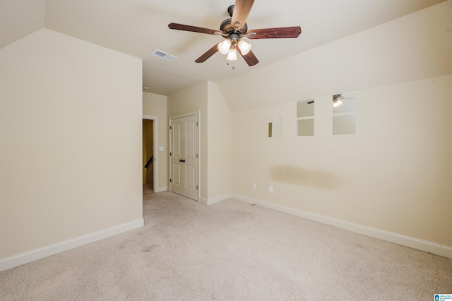 carpeted empty room with lofted ceiling, visible vents, ceiling fan, and baseboards