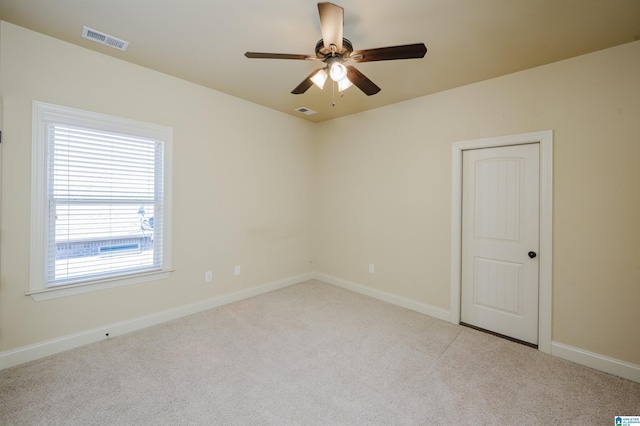 carpeted empty room featuring a ceiling fan, visible vents, and baseboards